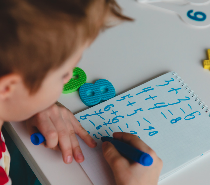 boy does math homework with blue marker
